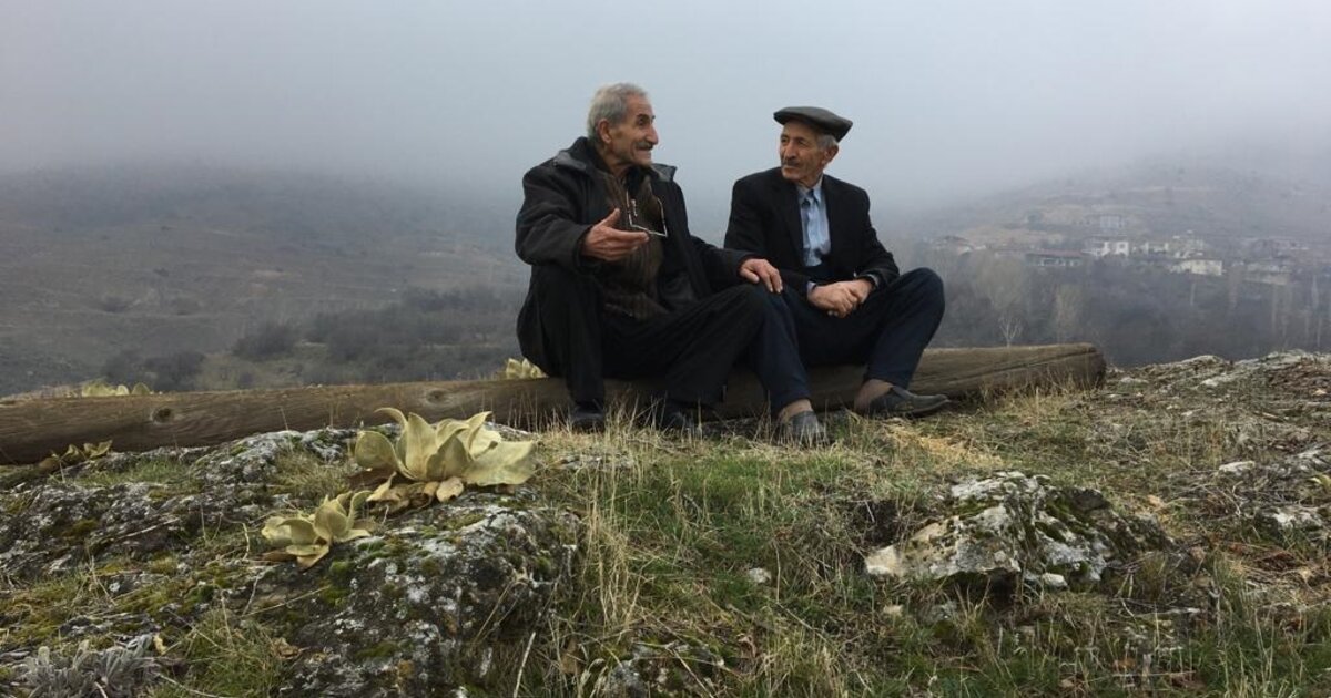 Zwei Männer sitzen in einer nebligen Landschaft